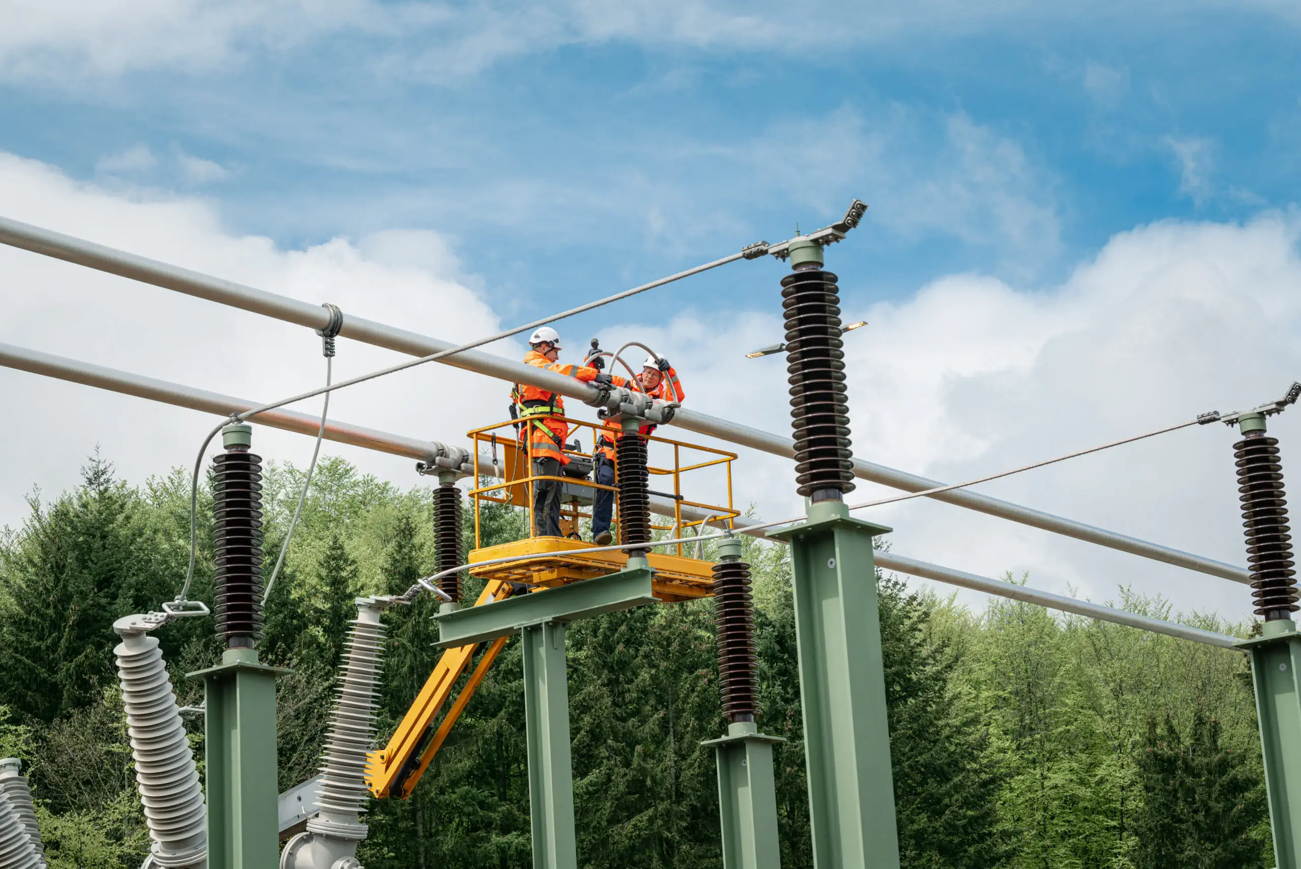 Zwei Menschen arbeiten an einem Umspannwerk.