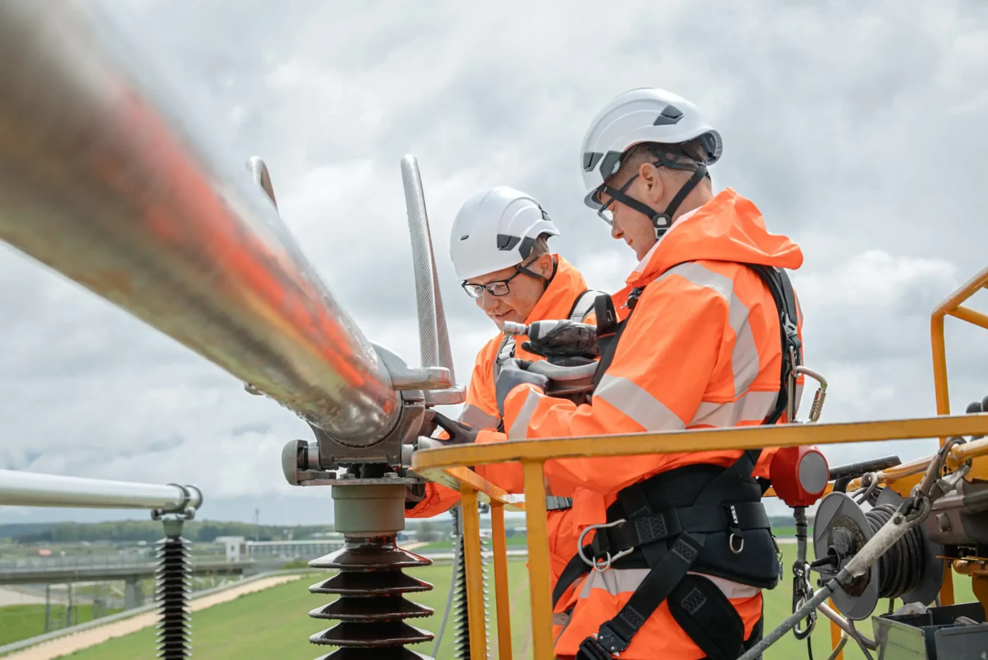 Zwei Menschen arbeiten an einem Umspannwerk.