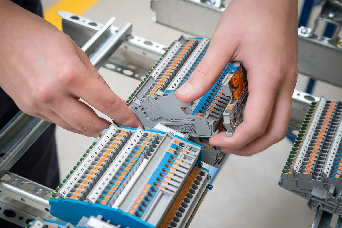 Ein Mensch arbeitet an einer Schaltanlage. Man sieht eine Detailtansicht seiner Hände.