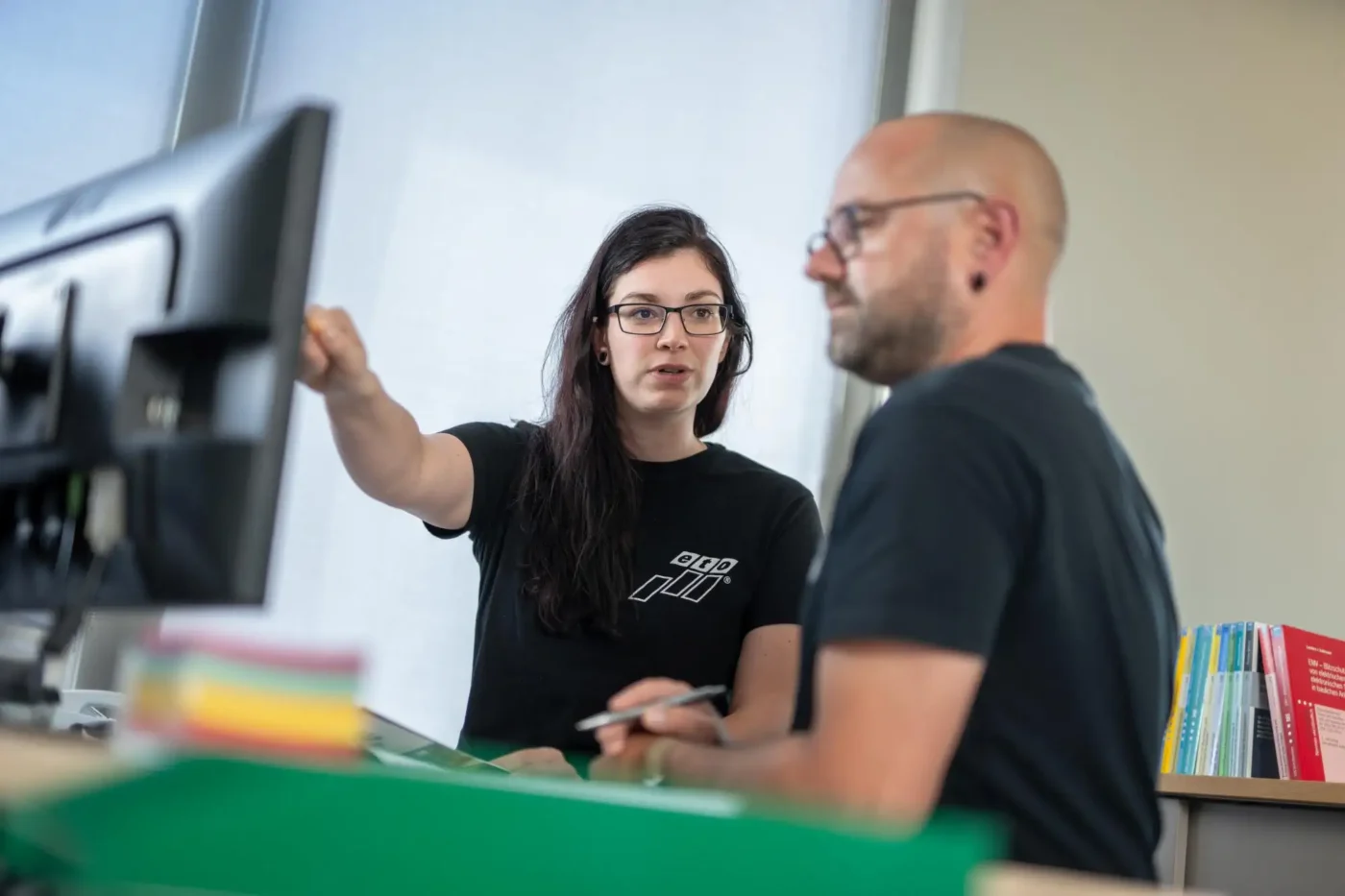 Zwei Menschen schauen auf einen Computerbildschirm.